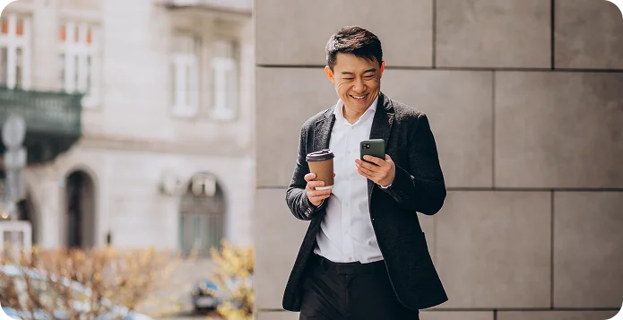 Smiling store manager checking his phone while holding a coffee